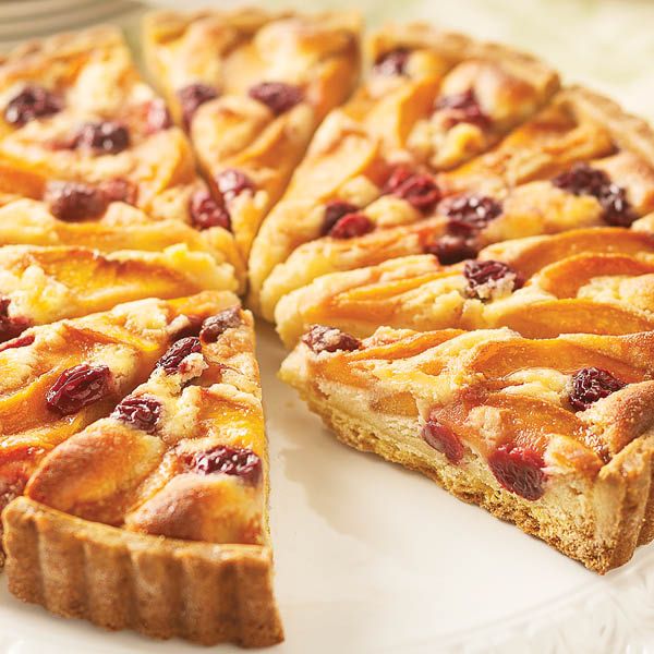 Sliced fruit tart with peach slices and cherries on golden crust