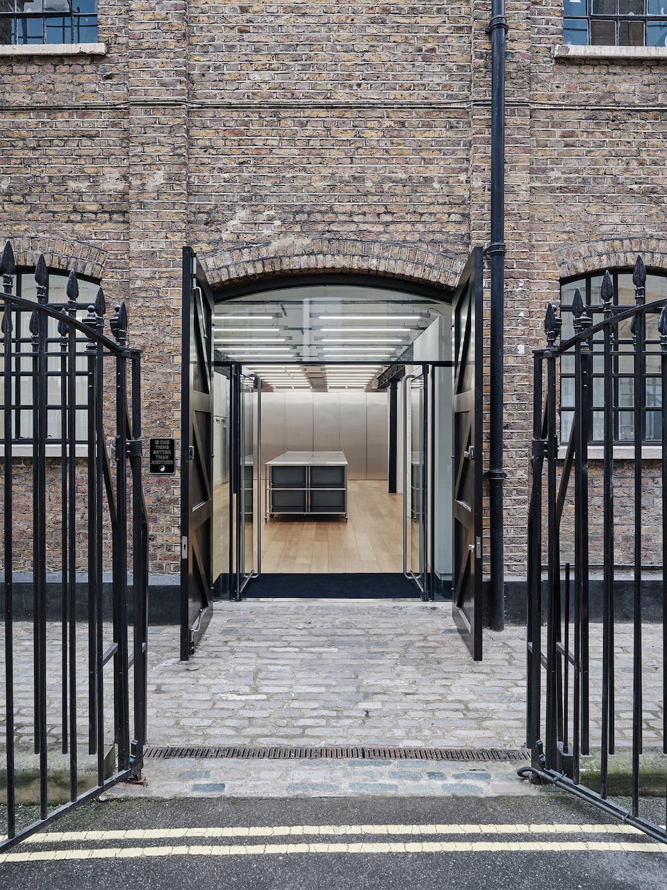 Brick building entrance with black iron gates and white canopy over glass door