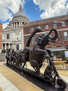 Bronze sculpture of elephant and animals on scooter with St Paul's Cathedral dome in background