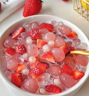 Bowl of strawberry jelly dessert with ice cubes and fresh strawberries