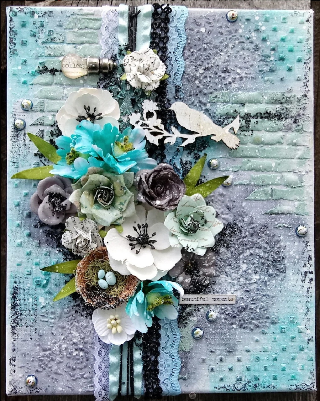 Mixed media art collage with turquoise and white paper flowers on textured grey background with lace and beads