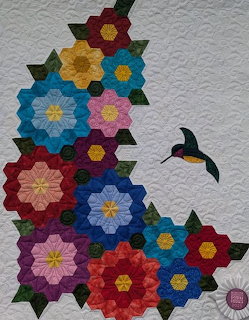 Patchwork quilt with hexagonal flower blocks in multiple colors and bird appliqués on white fabric