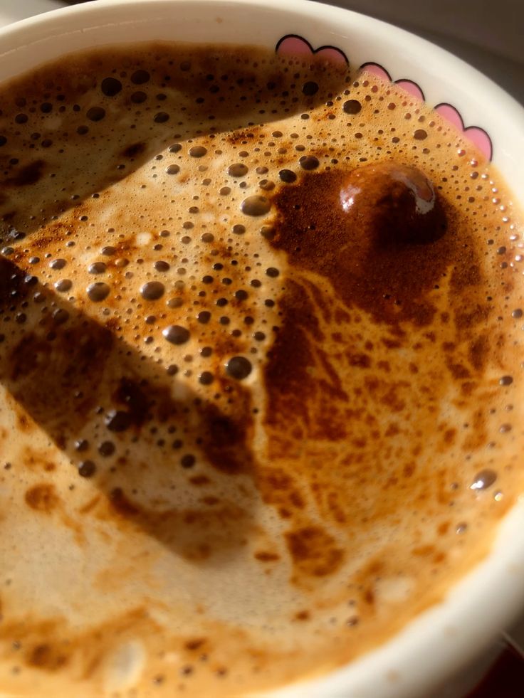 Close-up of foamy coffee in a white cup with brown crema and bubbles