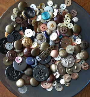 Assorted vintage buttons piled on a round tray in brown, black, white, and pastel tones.