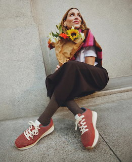 Woman in pink shirt and black skirt sitting on steps holding flower bouquet
