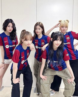 Four young women posing indoors in blue and red soccer jerseys