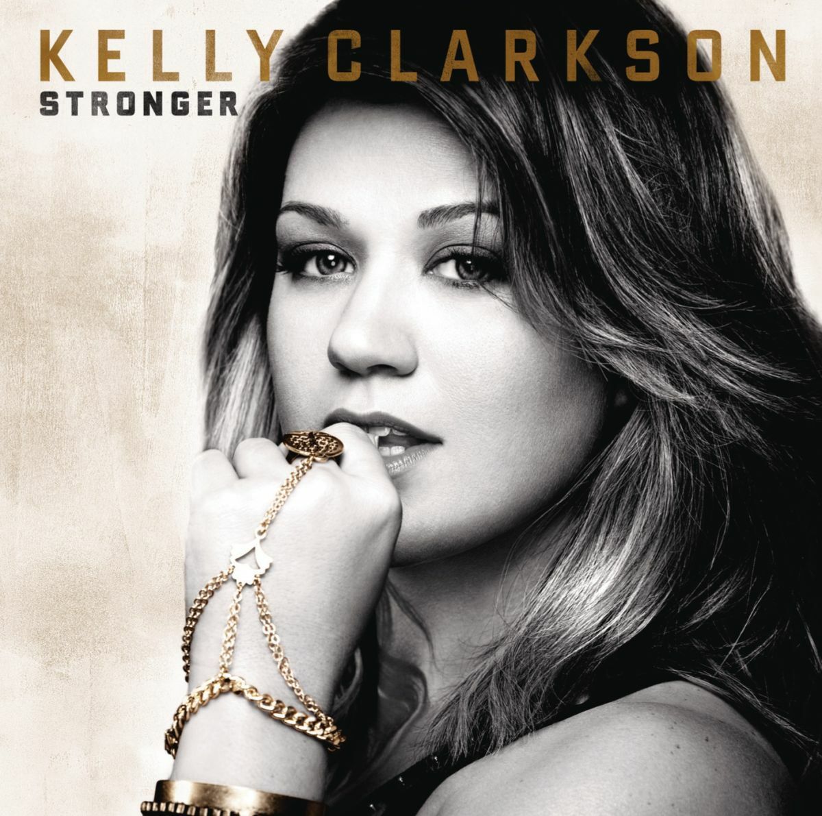 Black-and-white portrait of Kelly Clarkson with gold jewelry and text above