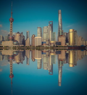 Shanghai skyline with skyscrapers reflected in still water under a clear blue sky