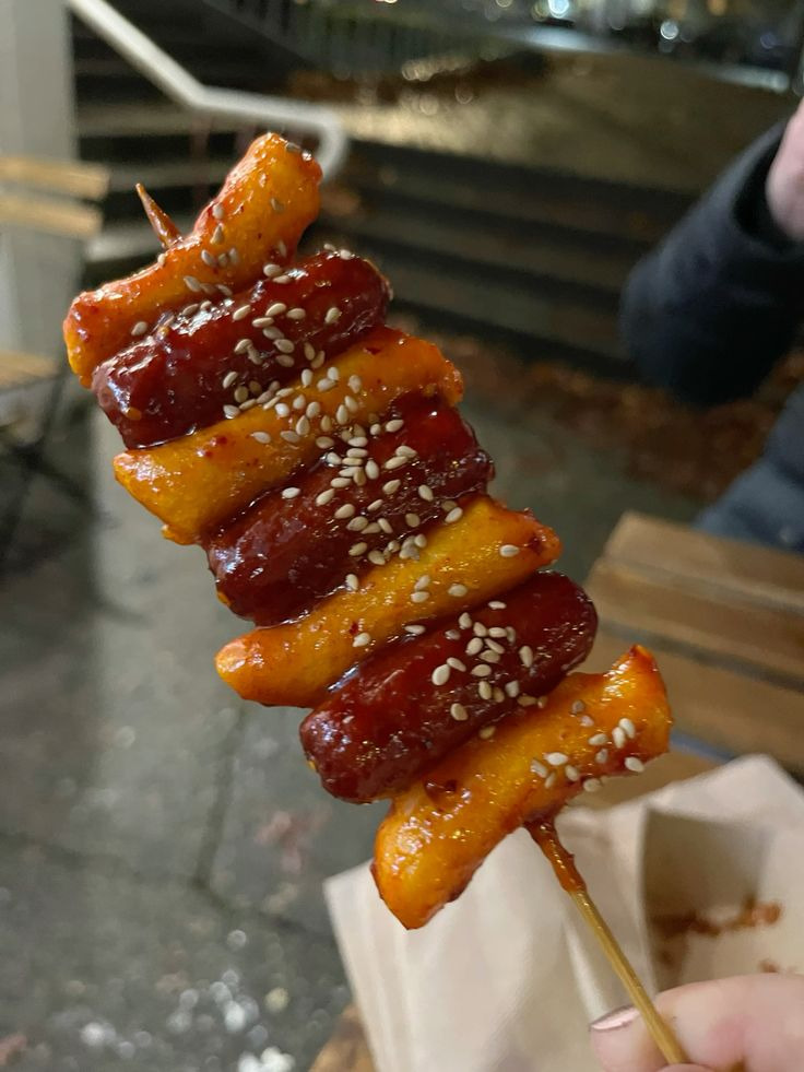 Glazed Korean sotteok sotteok skewer with sausage and rice cake pieces topped with sesame seeds