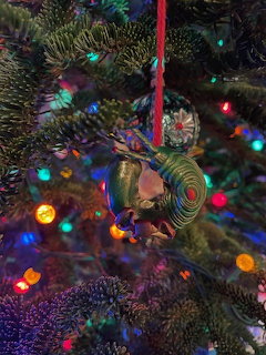 Slug-shaped ornament hanging on a Christmas tree with colorful lights