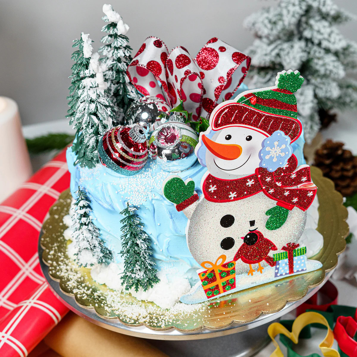 Christmas cake with snowman decoration, frosted trees, and candy canes on blue icing