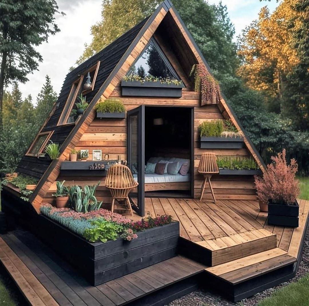 A-frame cabin with wooden deck and planters in forest setting