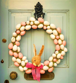 Pastel egg wreath with orange bunny and pink bow hanging on mint green door