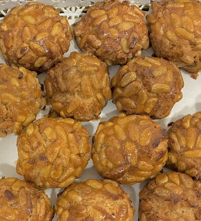Twelve round panellets pastries with pine nuts on white lace doily