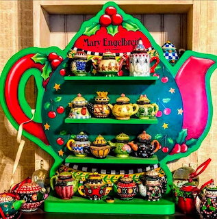 Teapot-shaped shelf with multiple decorative miniature teapots on tiered display