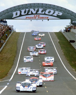 Group C race cars on the Le Mans track under the Dunlop bridge