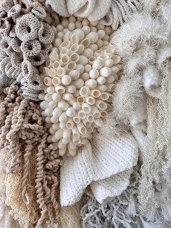White and beige fiber art sculpture with coral-like textures, beads, and organic reef-inspired forms