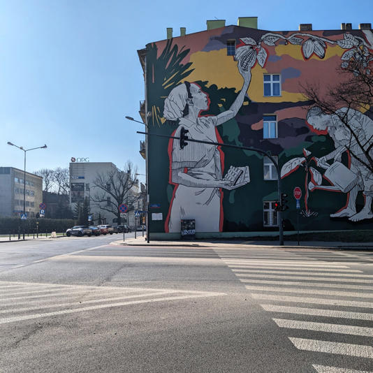 Colorful mural on the side of a building at a street intersection in Lodz, Poland
