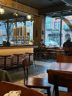 Modern coffee shop interior with tables, chairs, hanging lights, and large windows