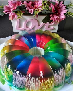 Rainbow colored ring gelatin dessert with pink flower decorations and love sign on top