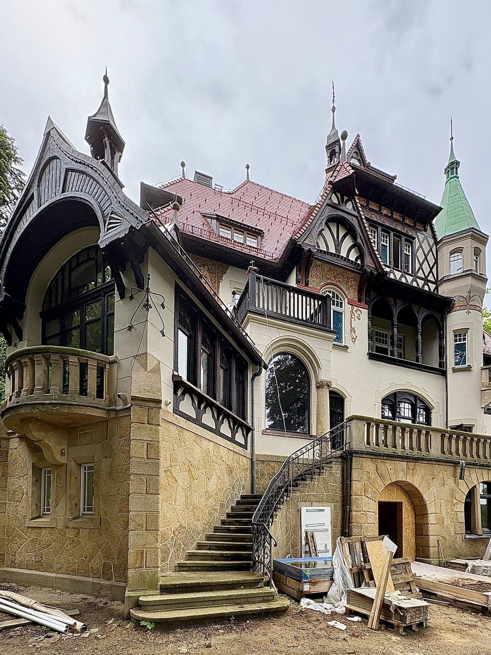 Historic ornate villa in Wrocław under renovation with Gothic architectural details, turrets, and exterior staircase