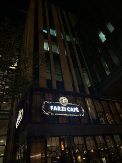 Tall building at night with illuminated Farzi Cafe sign above the entrance