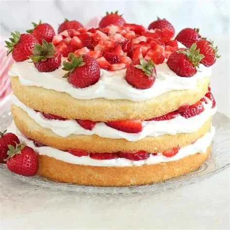 Layered strawberry shortcake with whipped cream and fresh strawberries on white plate