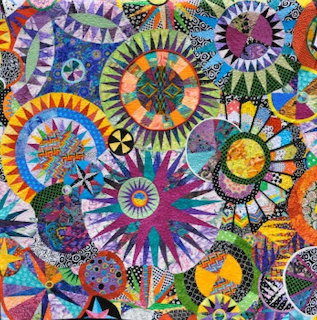 Colorful patchwork quilt with circular saucer patterns in purple, green, orange, and yellow radiating designs