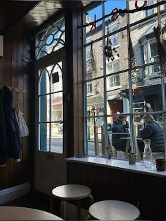 Cafe interior with stools and large window looking onto a sunny street