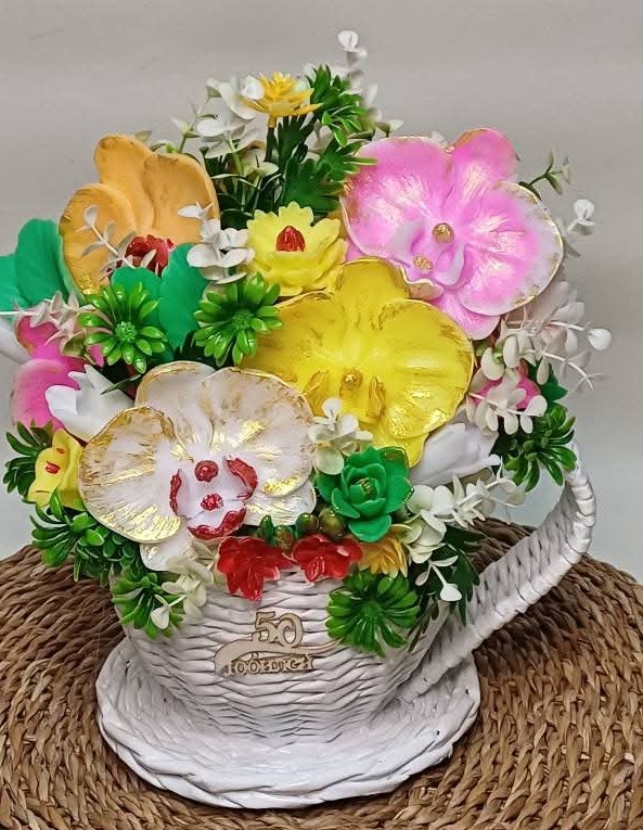 White wicker basket arrangement with colorful artificial flowers in pink, yellow, orange and white