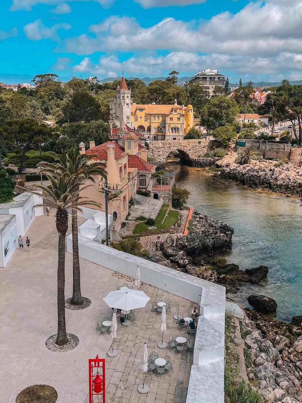 Pastel buildings and palm trees beside a rocky coastal inlet in a Portuguese town