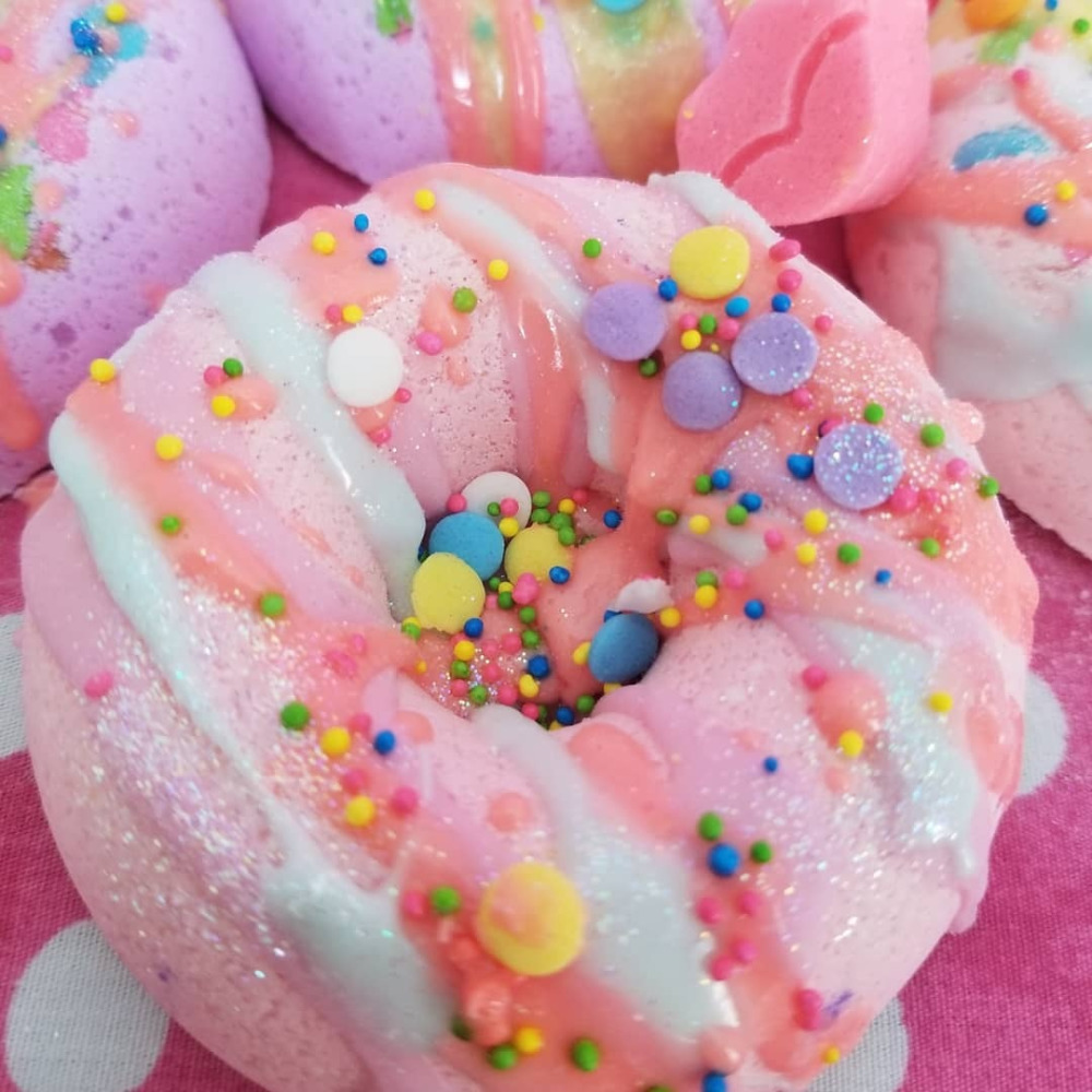 Close-up of pastel pink and white frosted donuts covered in colorful sprinkles and candy decorations