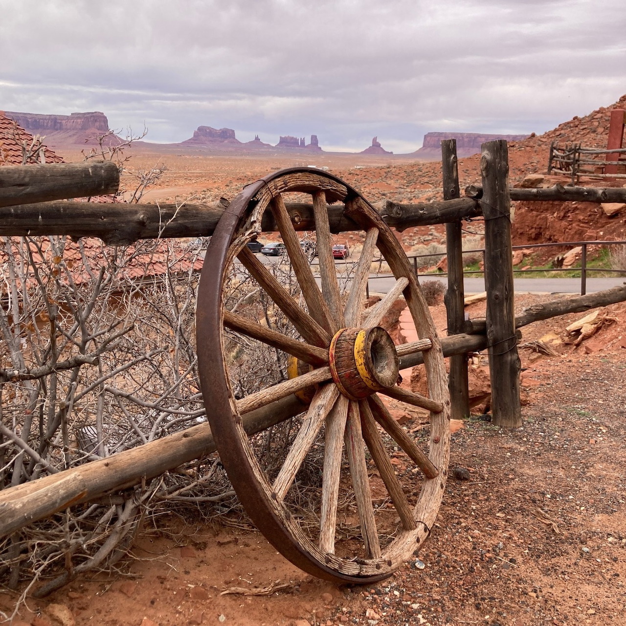 Old wagon wheel on a wooden fence in an Arizona desert landscape with red rock mesas