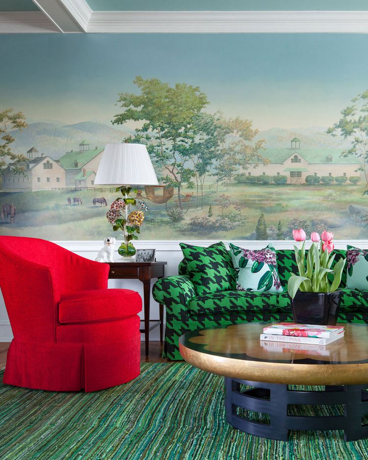 Living room with red armchair, green houndstooth sofa, round coffee table, and scenic wall mural