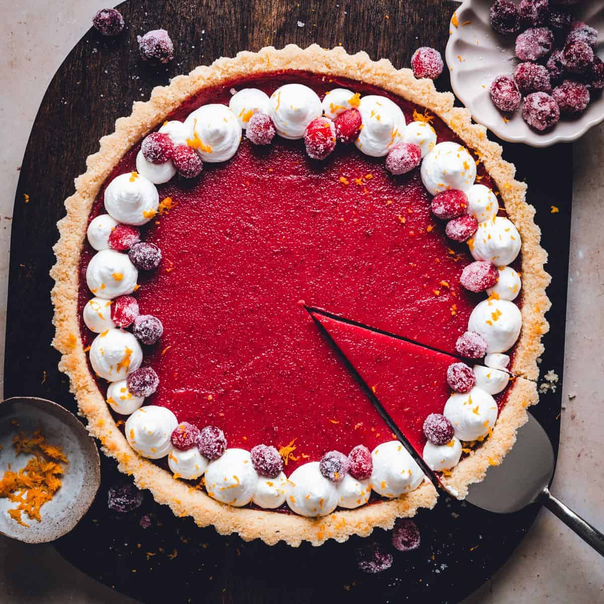 Top view of a cranberry tart topped with whipped cream and sugared cranberries