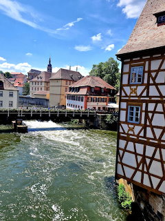 Half-timbered building next to a river weir in Bamberg old town with colorful historic buildings