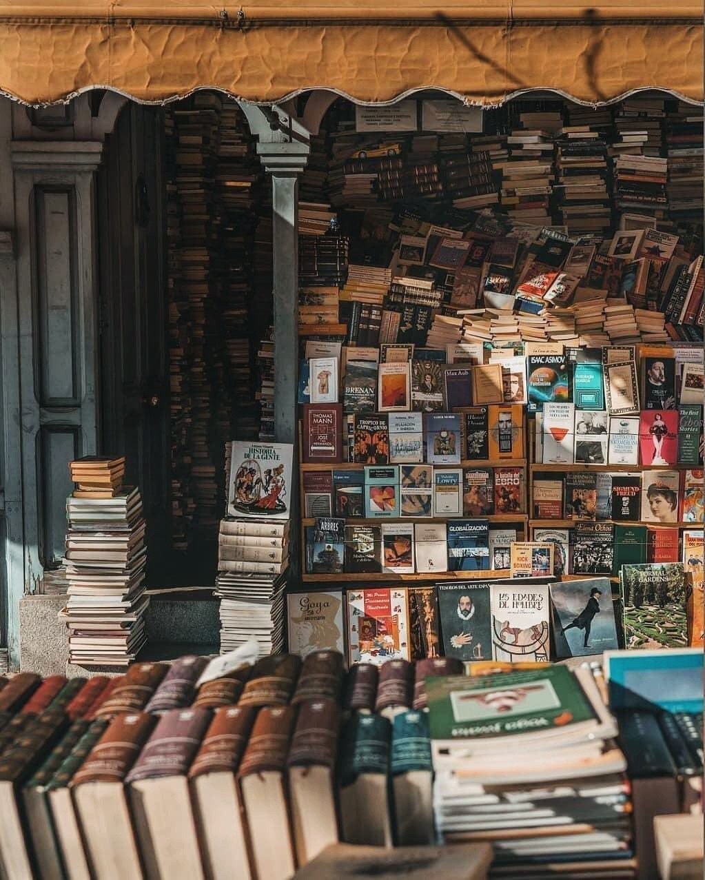 Outdoor bookstall with hundreds of colorful books stacked and displayed on shelves under an awning