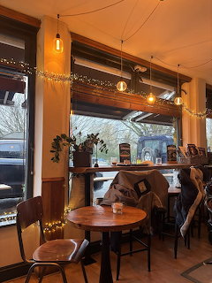 Cozy coffee shop interior with tables, chairs, windows, and warm string lights