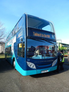 Blue double decker bus parked outdoors with a person boarding at the front door