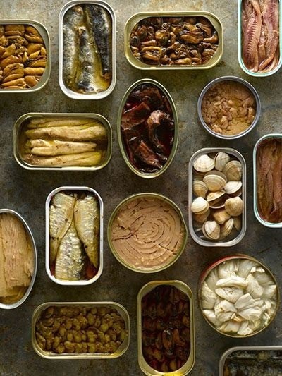 Assortment of opened canned fish, meats and seafood in tins viewed from above