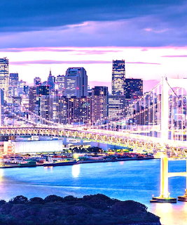 Tokyo skyline at dusk with lit bridge over bay and purple twilight sky