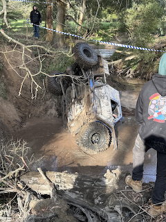Overturned 4x4 vehicle stuck upside down in a mudy creek during an off-road winch challenge