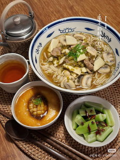 Top-down Korean-style meal with noodle soup, tea, custard, and cucumber side dish
