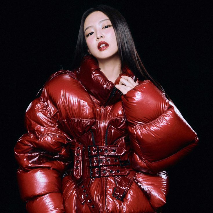 Woman in oversized metallic red puffer jacket with long dark hair on black background