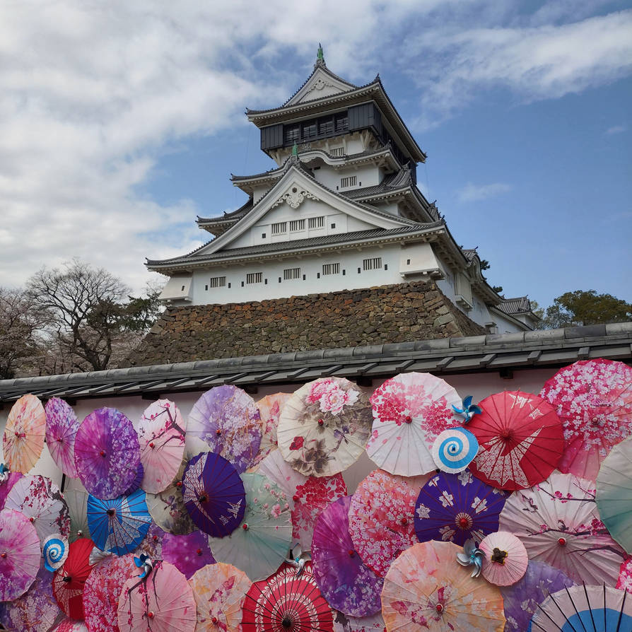 Japanese castle above a row of colorful paper umbrellas under a cloudy sky
