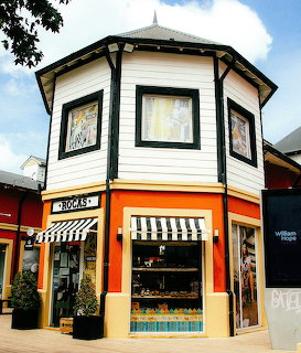 Octagonal boutique shop called Rocas with striped awnings and orange trim in a shopping village