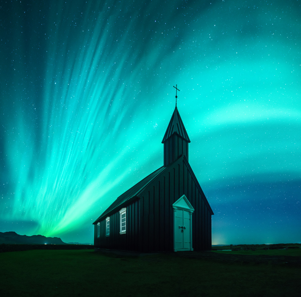 Black church beneath bright aurora borealis in a starry night sky