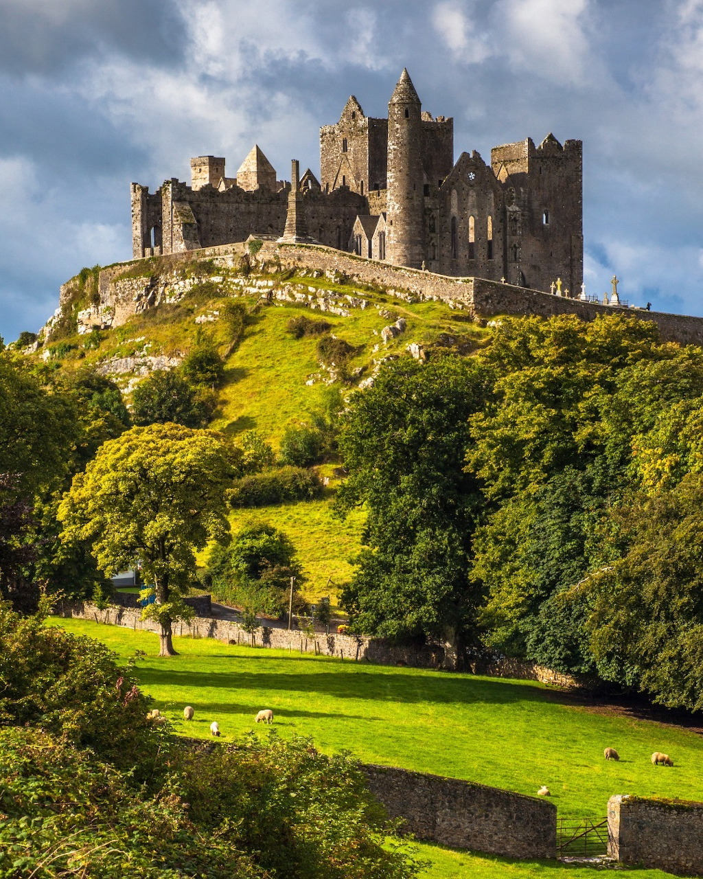 Medieval castle ruins on a hilltop with green slopes and blue sky
