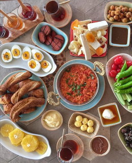 Overhead view of a traditional Turkish breakfast spread with eggs, simit, menemen, cheese, and tea