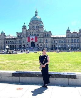 Woman posing in front of the British Columbia Legislative Assembly building with a Canadian flag